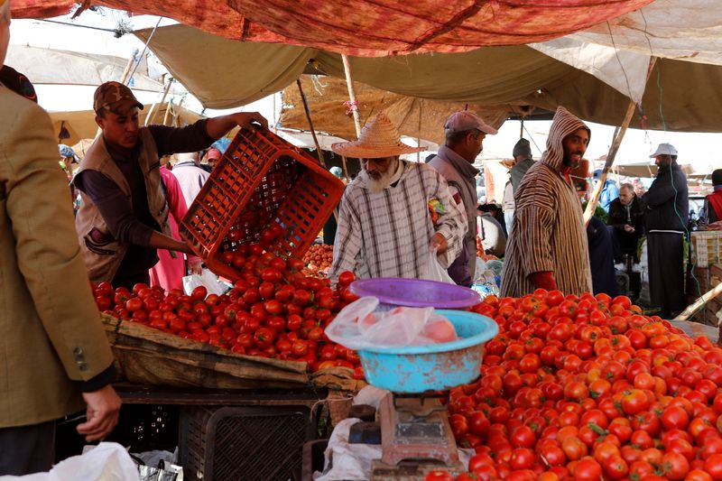 People shop at a vegetable market on the outskirts of