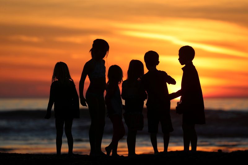 FILE PHOTO: Children watch the sun set as they inspect
