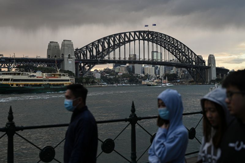 People walk in front of the Sydney Harbour Bridge in