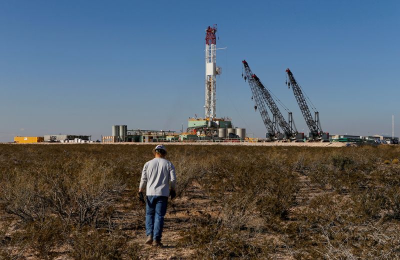 FILE PHOTO: An oil worker walks towards a drill rig