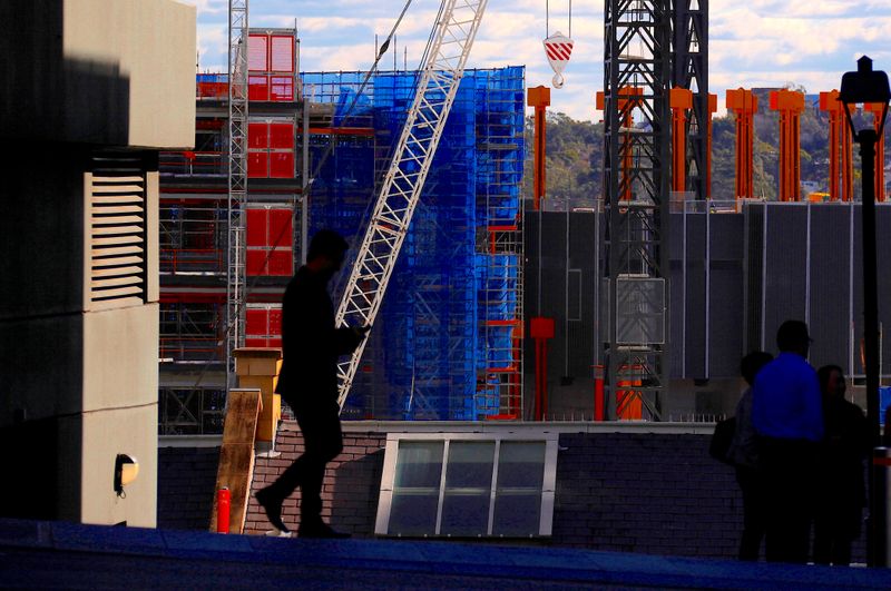 Pedestrians walk in front of a crane and scaffolding on