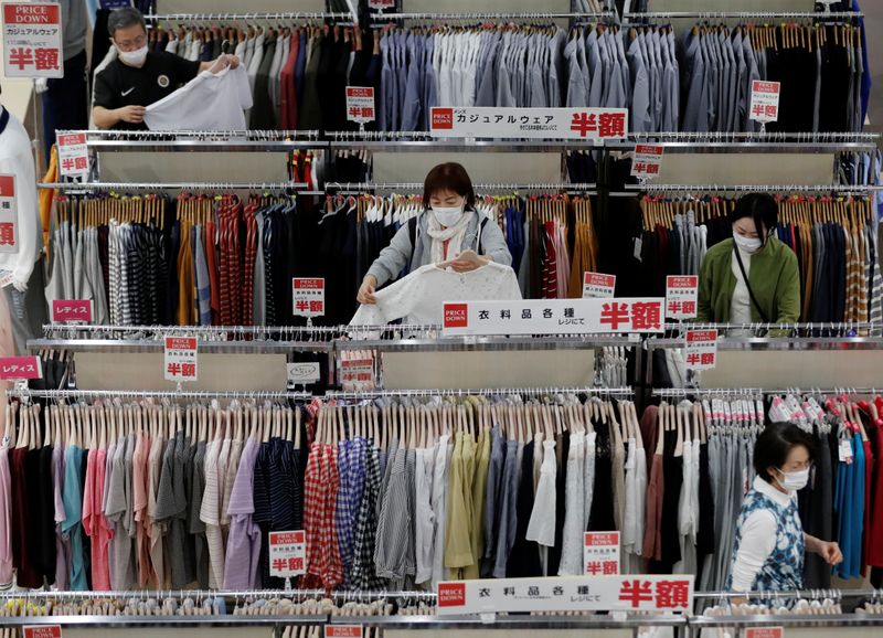 FILE PHOTO: Shoppers wearing protective masks choose clothes at Japan’s