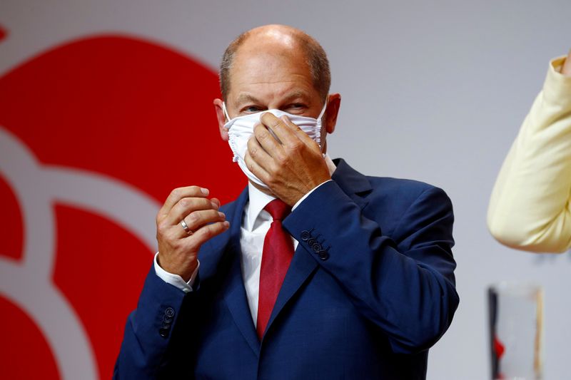 FILE PHOTO: Olaf Scholz adjusts his protective face mask after