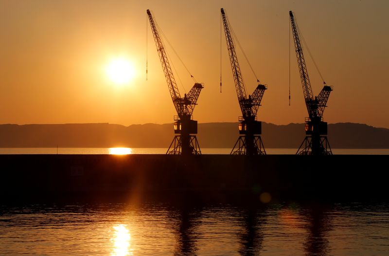 The sun sets behind loading cranes in the old harbour