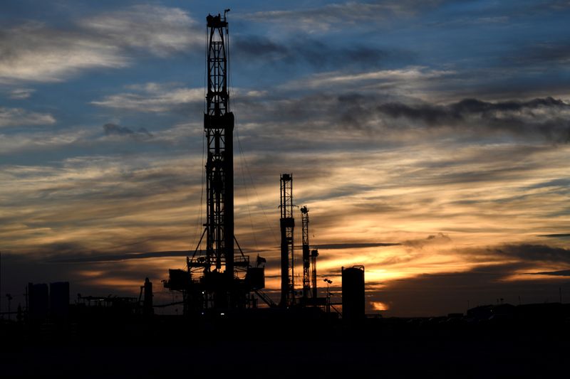 FILE PHOTO: Drilling rigs operate at sunset in Midland