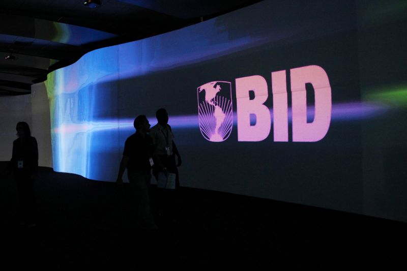 FILE PHOTO: Visitors walk past a screen with the logo