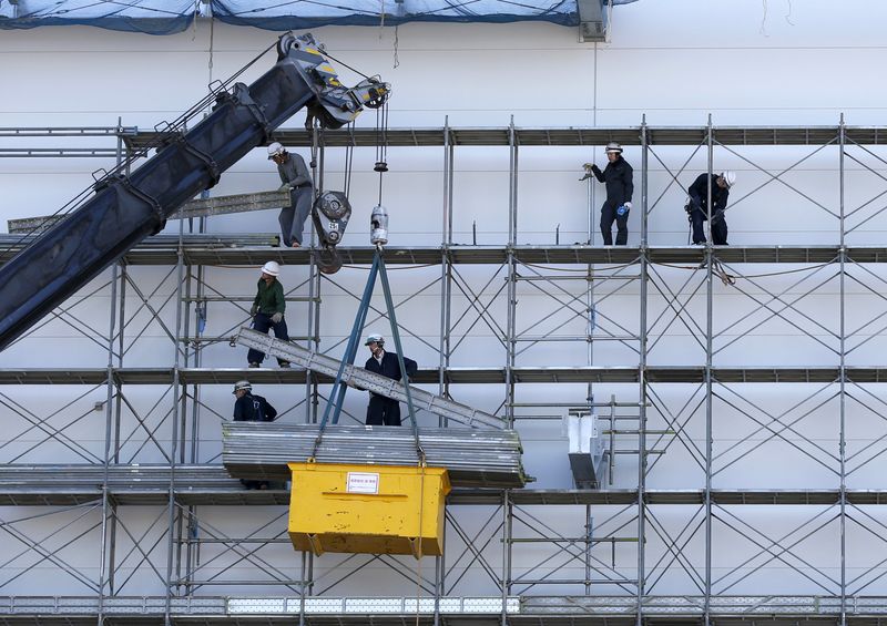 FILE PHOTO: Men work near a crane at a construction