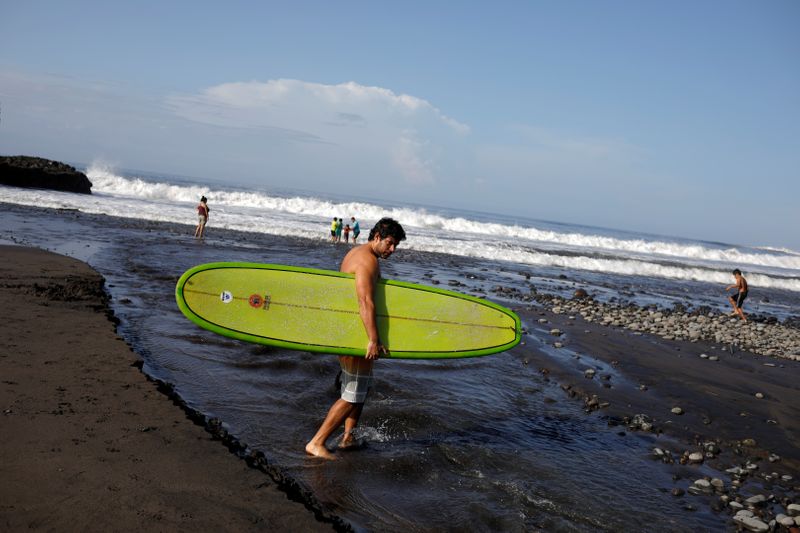 FILE PHOTO: Surfer crosses a stream at El Tunco beach