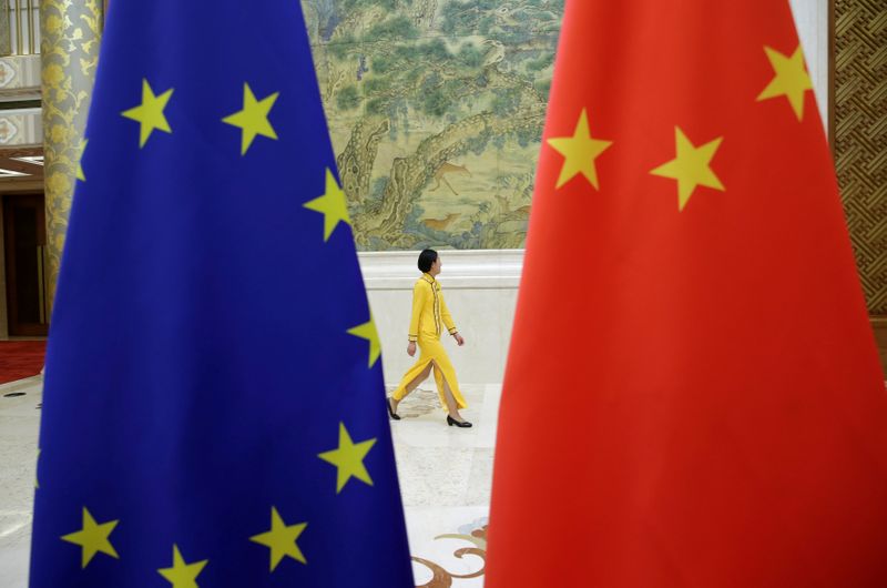 An attendant walks past EU and China flags ahead of