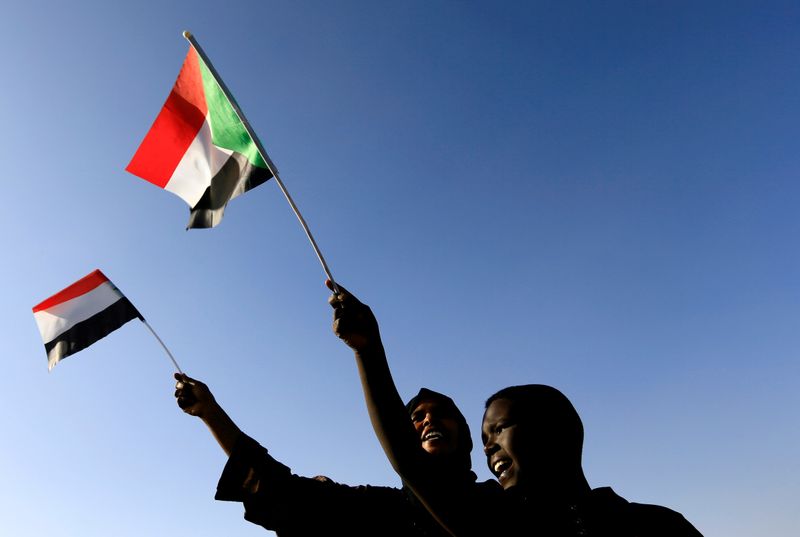 FILE PHOTO: Sudanese civilians wave their national flag as they