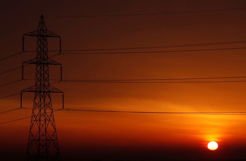 FILE PHOTO: The sun is seen behind high-voltage power lines