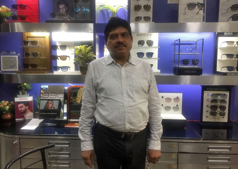 Gajendra Sharma poses inside his shop selling eye glasses in