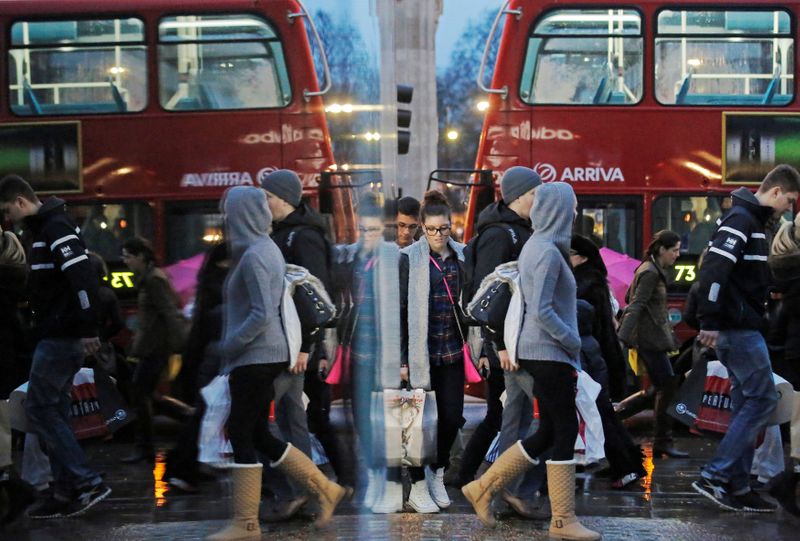 Shoppers are reflected in a shop window as they walk
