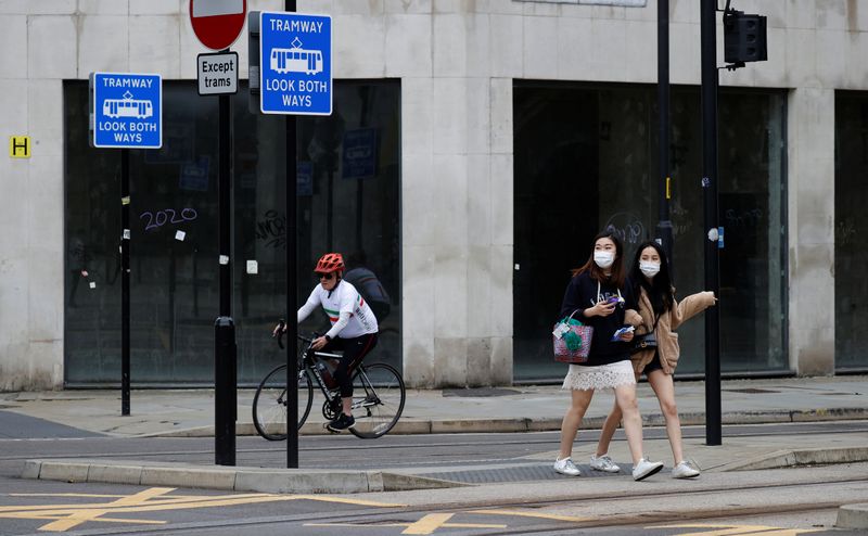 People wearing protective face coverings walk past an empty retail