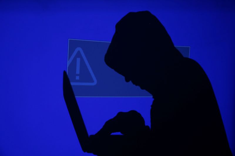 Hooded man holds laptop computer as blue screen with an