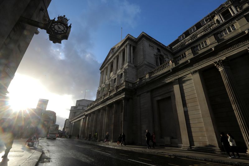 Pedestrians walk past the Bank of England in the financial