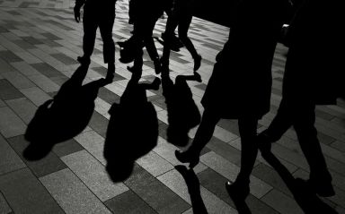 FILE PHOTO: Workers cast shadows as they stroll among the