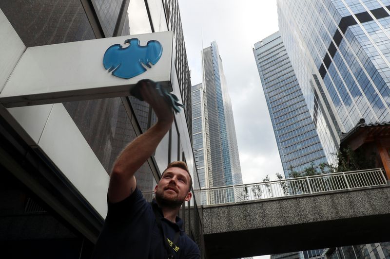 FILE PHOTO: A worker cleans a Barclays logo outside a