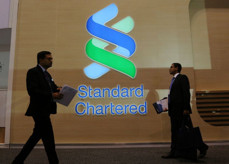 People pass by the logo of Standard Chartered plc at