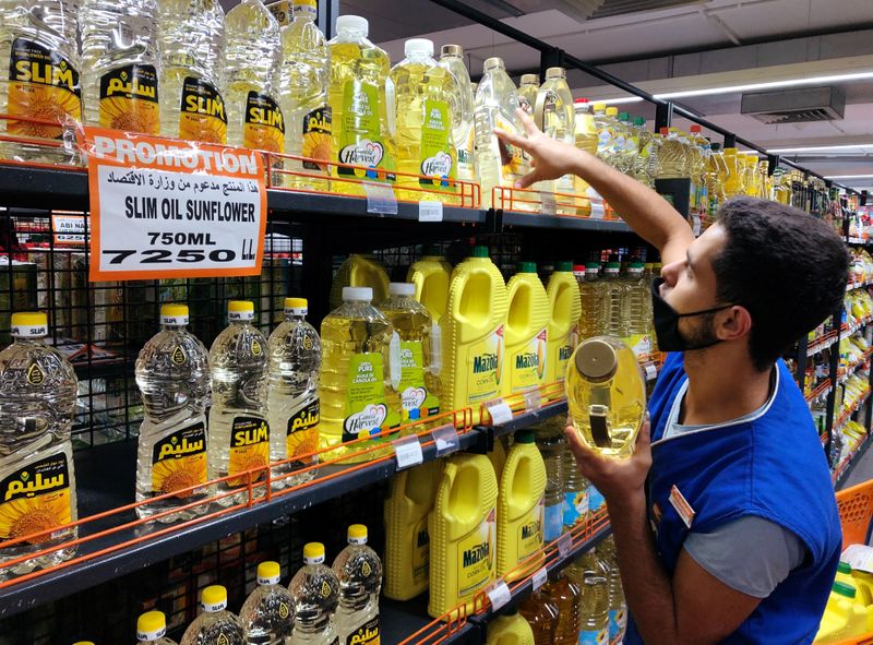 A worker arranges bottles of oil inside inside a supermarket