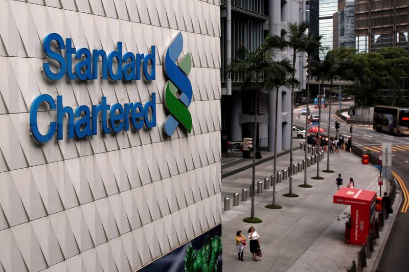 People walk outside the main branch of Standard Chartered in
