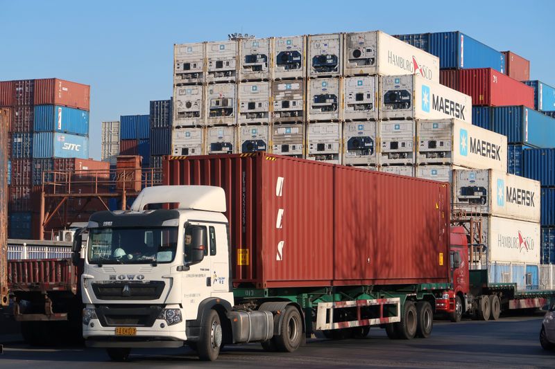 Worker drives a truck carrying a container at a logistics