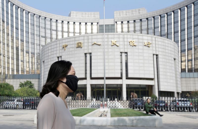 A woman walks past the headquarters of the PBOC, the