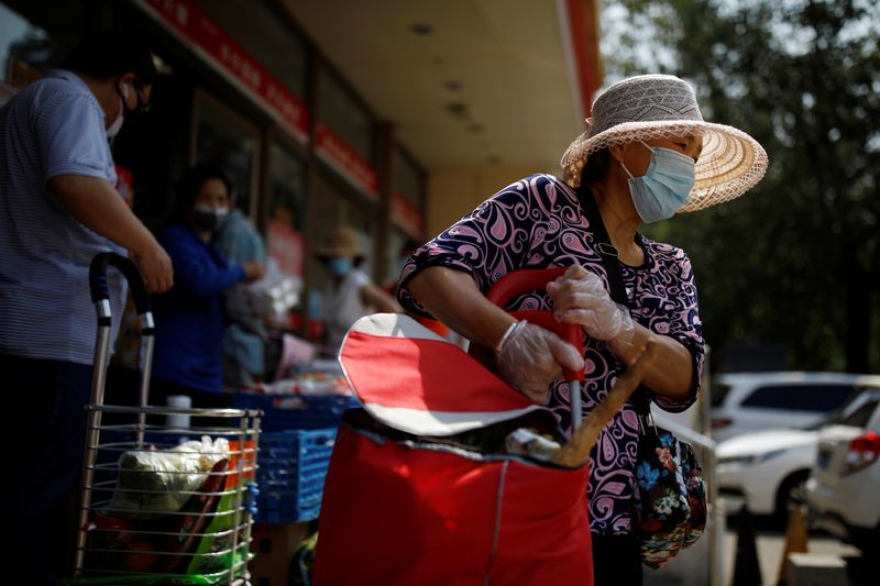 Woman holds a trolley outside a supermarket in Beijing