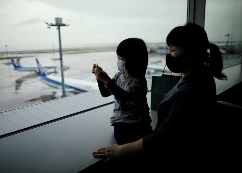 A family members wearing protective face masks watch airplanes, amid