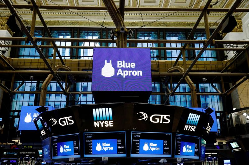 The logo of Blue Apron is shown on screens above