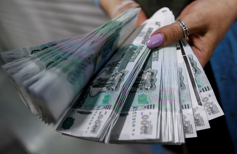 FILE PHOTO: An employee holds 1,000 Russian Roubles notes at