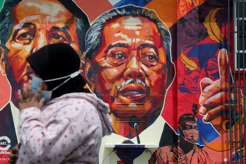 A woman passes by a mural depicting Malaysia’s Prime Minister