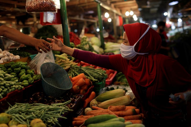 A woman wearing a protective mask shops for vegetables at