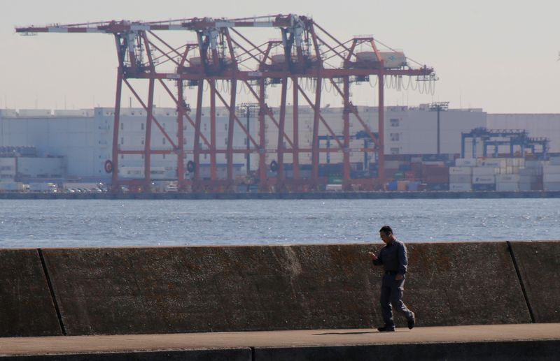 Men are seen in front of containers and cranes at