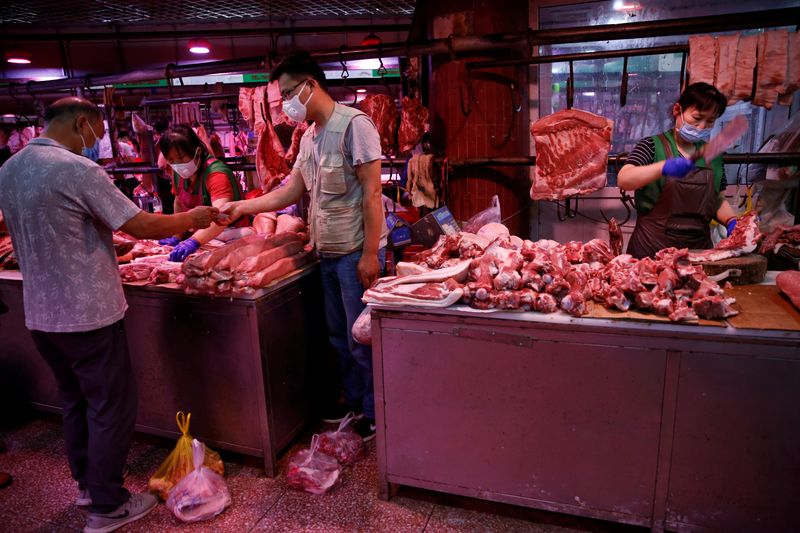 customer wearing a face mask pays for pork as a