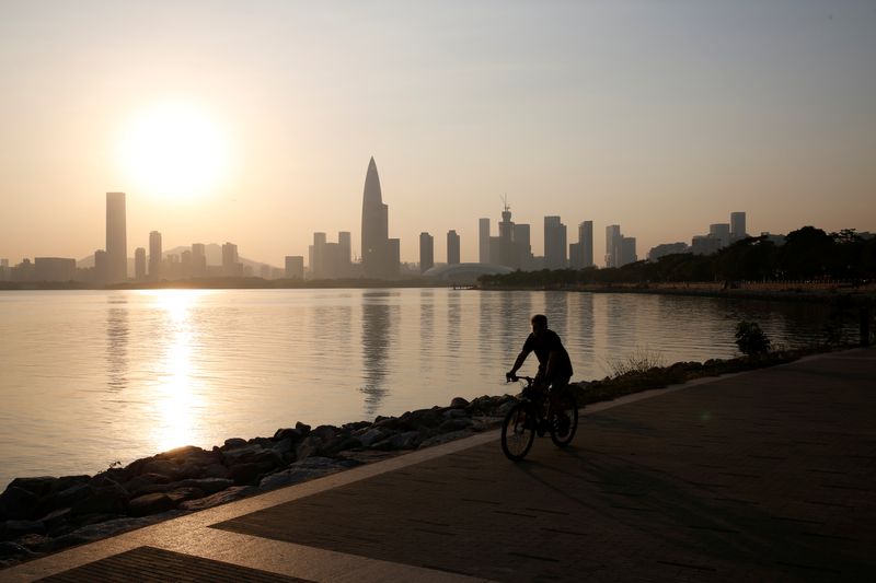 A person rides a bicycle during sunset in front of