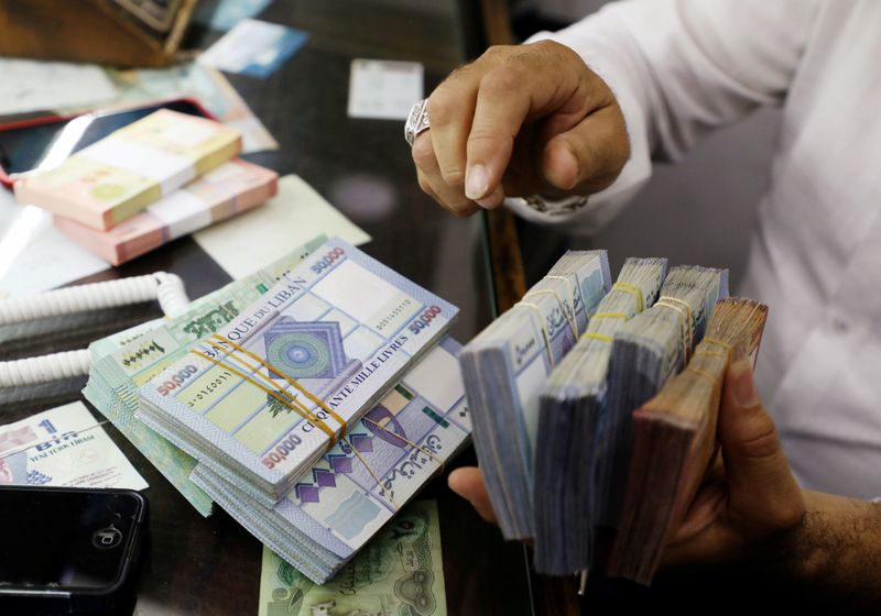 FILE PHOTO: A man counts Lebanese pounds at a currency