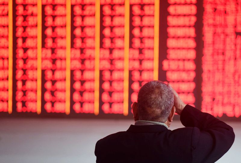 Man sits in front of an electronic board showing stock