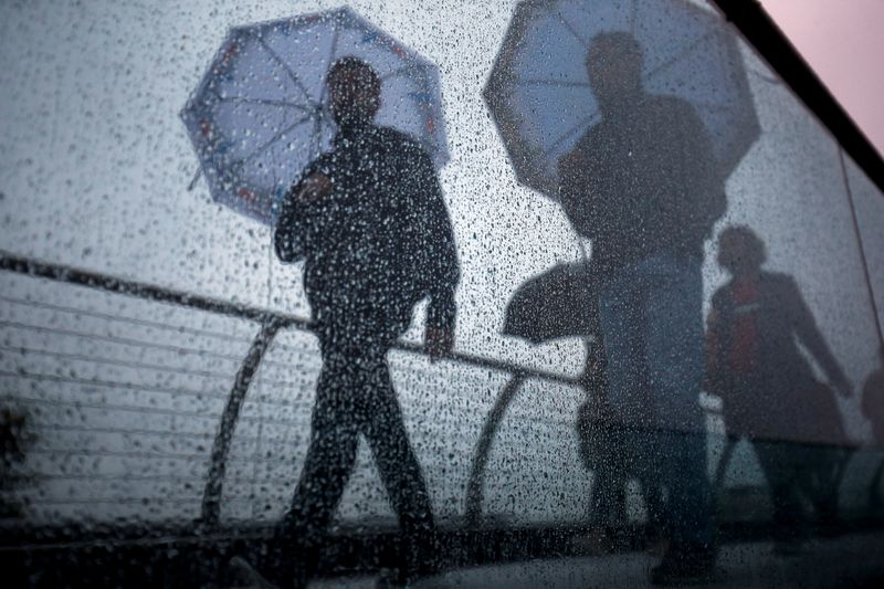 FILE PHOTO: Pedestrians walk across the Millennium Footbridge during rainy