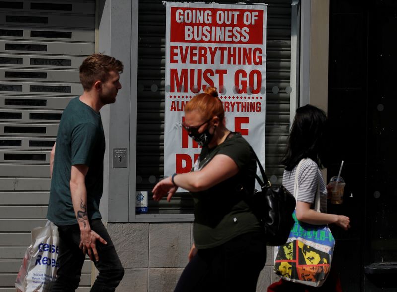 People walk past a closed shop following the outbreak of