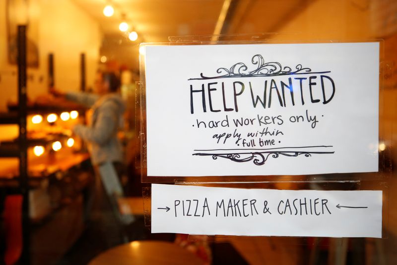 A “Help wanted” sign is seen in the window of