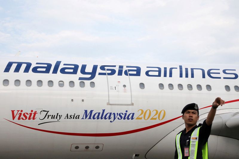 FILE PHOTO: An airport employee beside a Malaysia Airlines plane