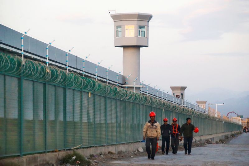 FILE PHOTO: Workers walk by the perimeter fence of what