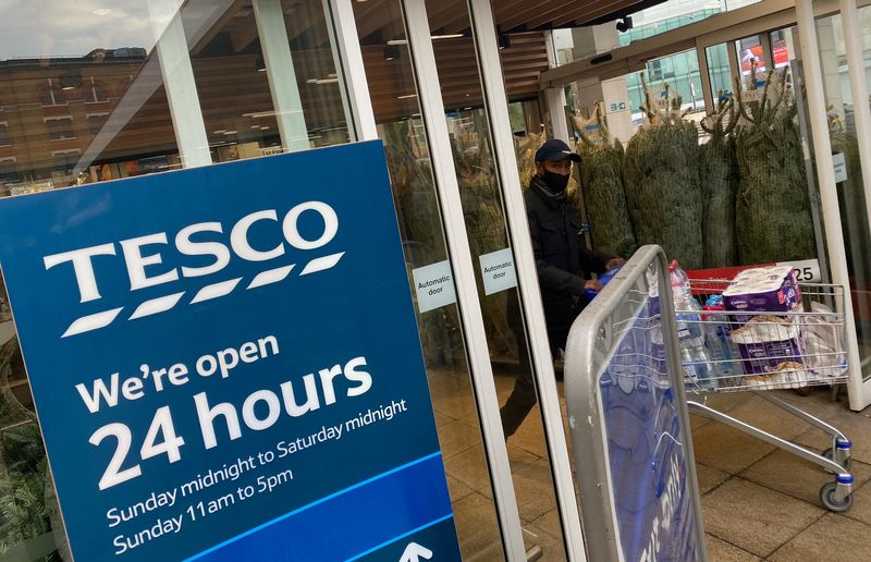 A shopper passes christmas trees for sale at Tesco supermarket