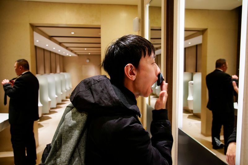 Liu Yuxuan, 22, a student, puts on his make-up at