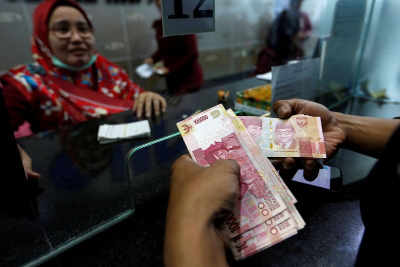 FILE PHOTO: A customer holds Indonesian rupiah bank notes at