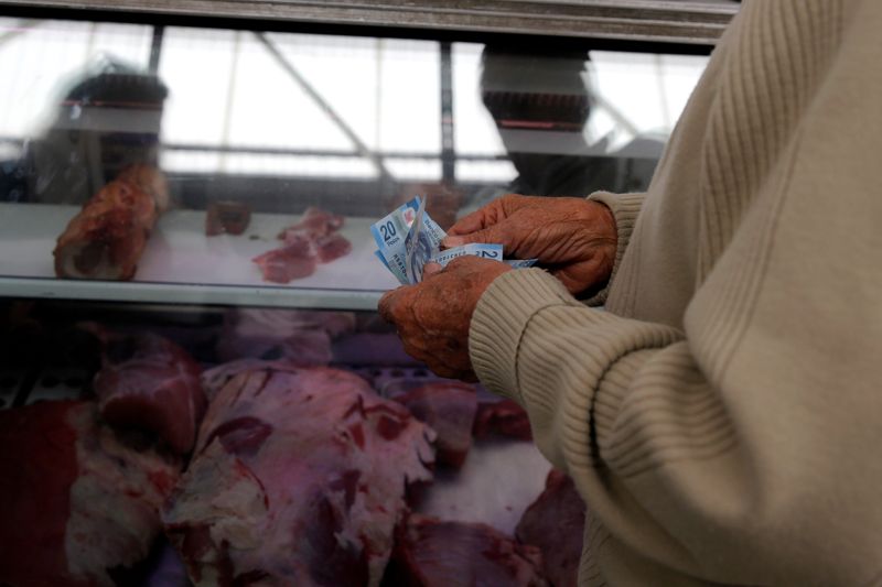 Man counts money to pay meat products at Granada market