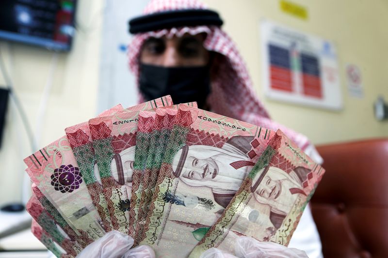 FILE PHOTO: A Saudi money exchanger wears a protective face