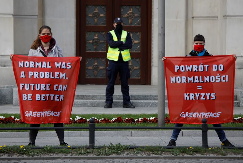 Environmental activists hold banners in front of the Polish Prime