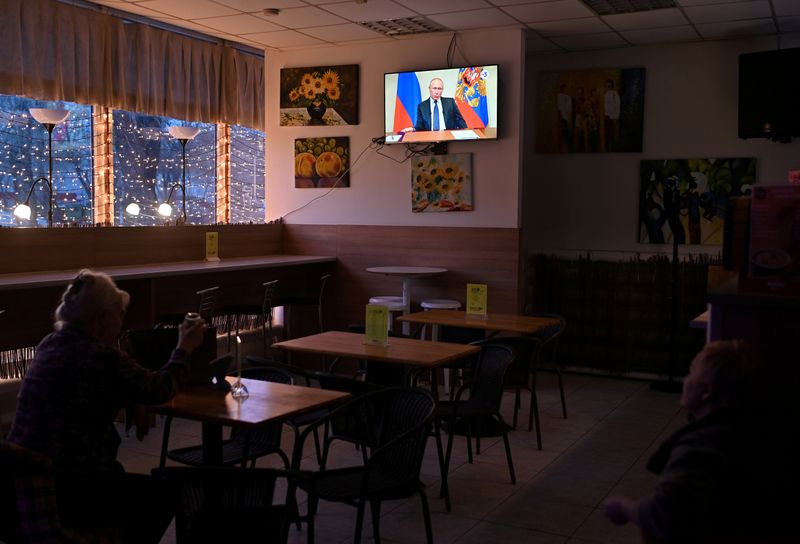 FILE PHOTO: People watch a broadcast of Russian President Vladimir